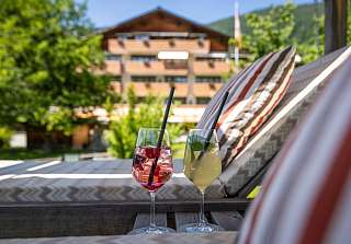 Two cocktails on a lounge terrace at Sunstar Hotel Klosters on a sunny day