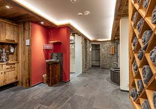 Stylish wellness area with wooden shelves, folded towels, stone walls and modern spa facilities at Sunstar Hotel Klosters