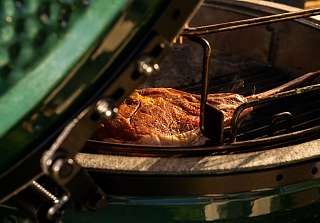 Marinated cut of meat on the grill of the Big Green Egg in the evening light, BBQ evening at Sunstar Hotel Klosters
