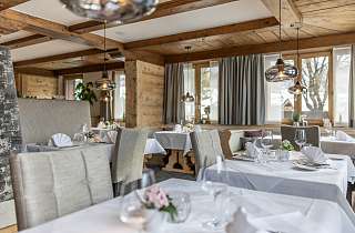 Hell und stilvoll gedeckte Tische mit weissen Servietten und Blumendekoration in der Boscastube des Sunstar Hotels Klosters