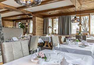 Tables élégamment dressées avec serviettes blanches et décoration florale dans la Bosca Stube du Sunstar Hotel Klosters