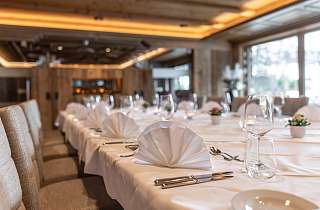 Lang gedeckte Banketttafel mit weissen Servietten, Weingläsern und Blumendekoration im Saal Boscablick des Sunstar Hotels Klosters