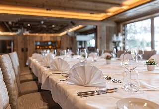 Lang gedeckte Banketttafel mit weissen Servietten, Weingläsern und Blumendekoration im Saal Boscablick des Sunstar Hotels Klosters