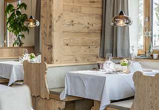 Laid tables with carved wooden benches and a reclaimed wood wall in the Bosca Stube at the Sunstar Hotel Klosters