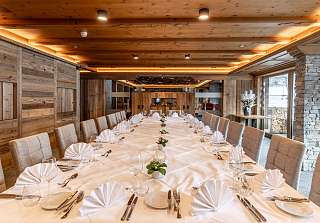 Festlich gedeckter langer Tisch mit weissen Servietten und Blumendekoration im Saal Boscablick des Sunstar Hotels Klosters