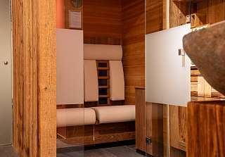 Modern infrared sauna with white loungers and glass door