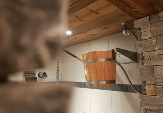 Wooden bucket shower in the spa with natural stone wall and shower area